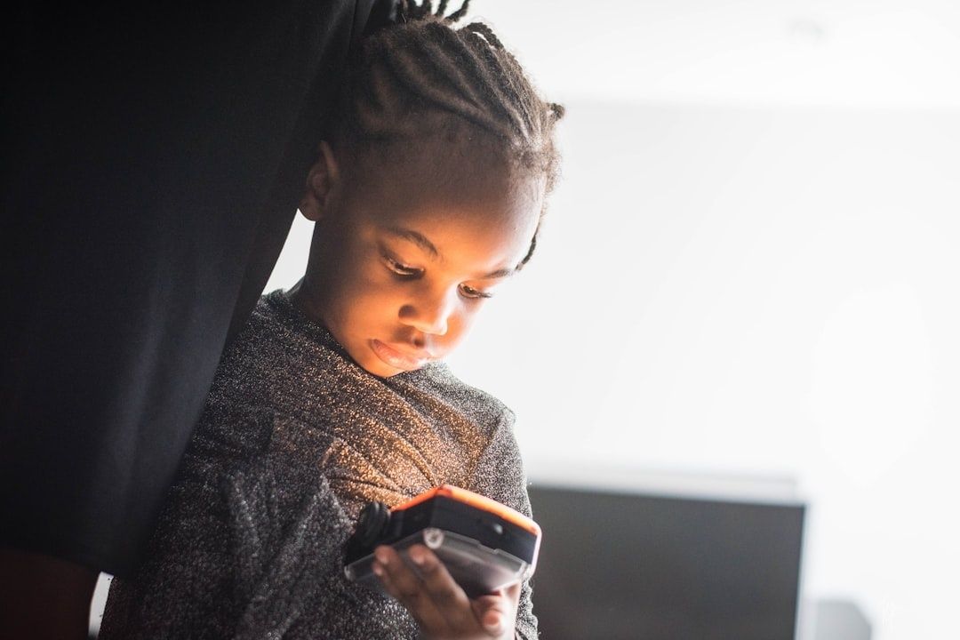 Young child looking at a smartphone while seated beside an adult