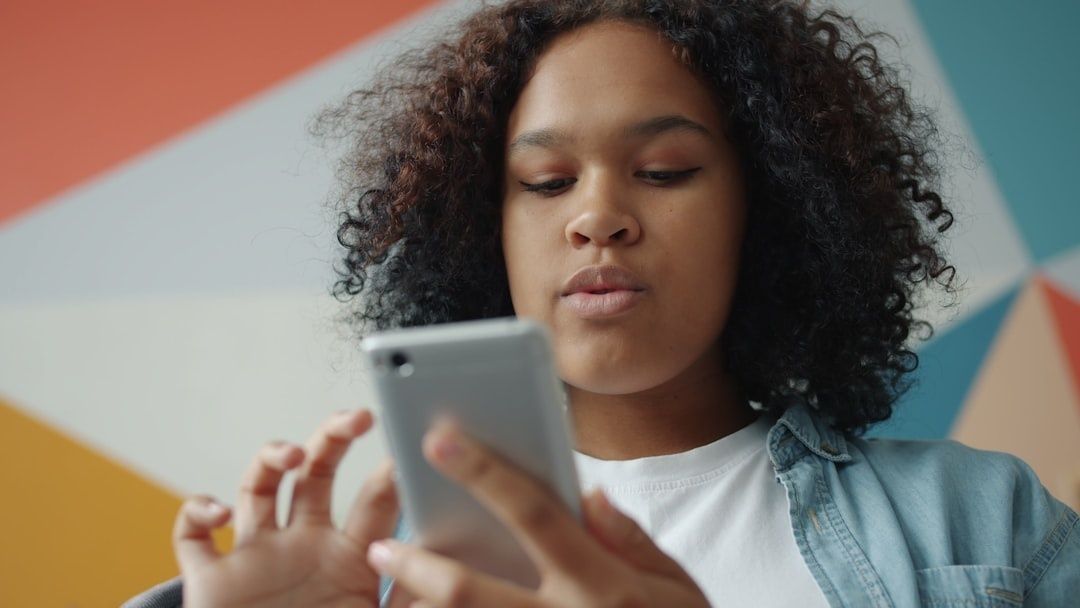 Young person looking thoughtfully at a smartphone
